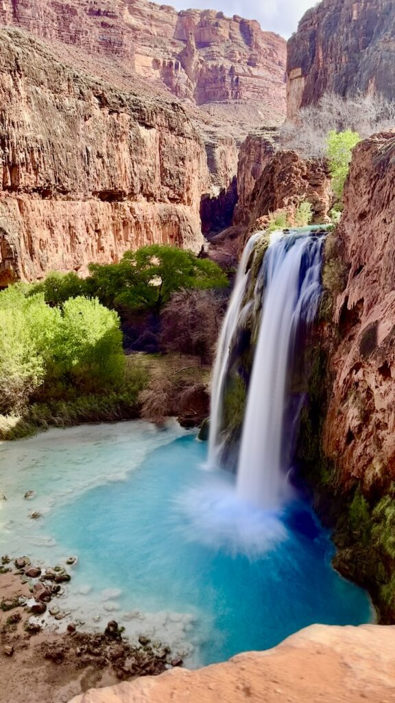 Havasu Falls waterfall in Arizona featuring turquoise blue water, red canyon walls, and scenic hiking trails
